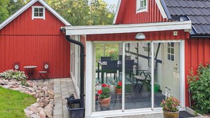 A red building with a white-framed glass door leading to an outdoor patio with a table and chairs. - Pet friendly home in Perstorp with WiFi (Perstorp)