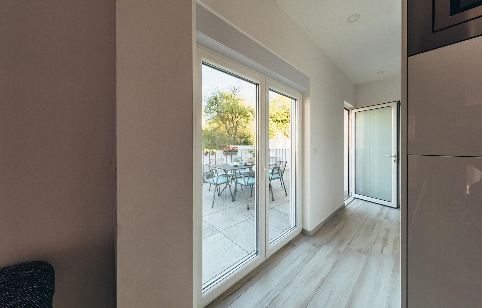 A modern kitchen with large sliding glass doors leading to an outdoor patio area.