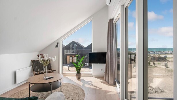 A modern room with a large window, a flat-screen TV, a dining table, and a potted plant. - Amazing apartment in Slagelse (Slagelse)