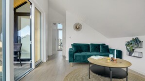 A modern living room with a green velvet sofa, a round coffee table, and a decorative wall piece. - Amazing apartment in Slagelse (Slagelse)