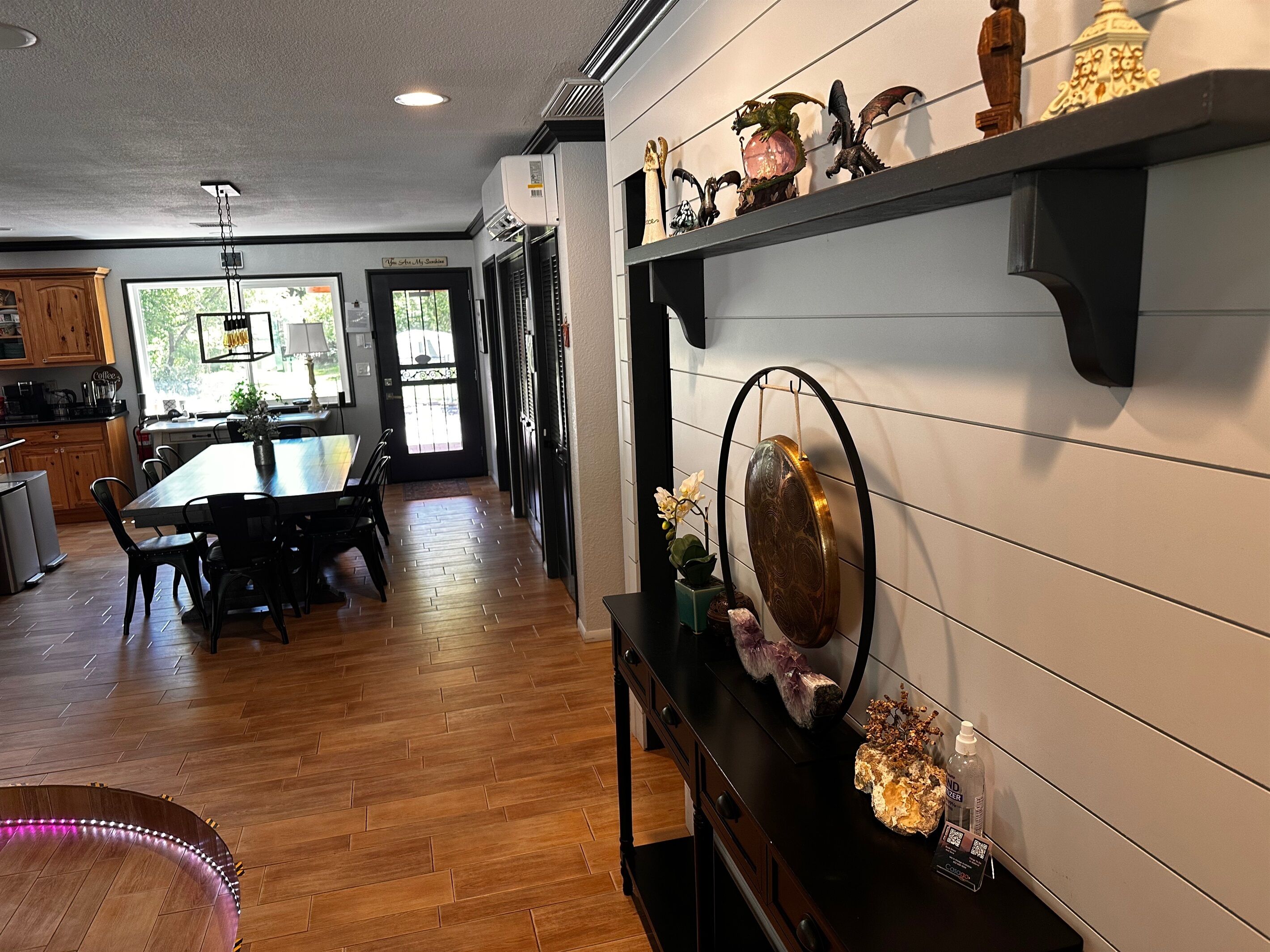 Una cocina con armarios de madera, una mesa de comedor, sillas y un estante decorativo.