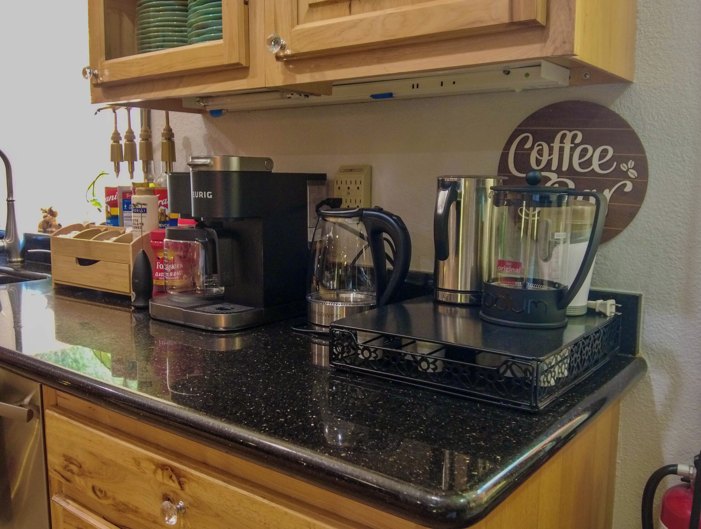 A kitchen counter with a coffee maker, a glass carafe, and a coffee pot.