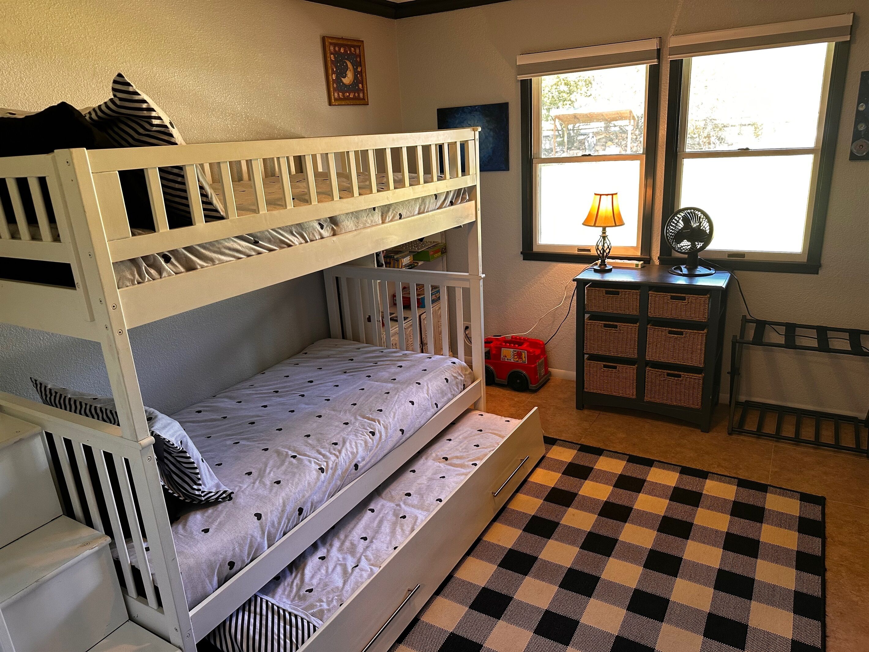 Ein Zimmer mit Etagenbetten, einem Fenster mit Blick, einer Lampe und einem Ventilator.