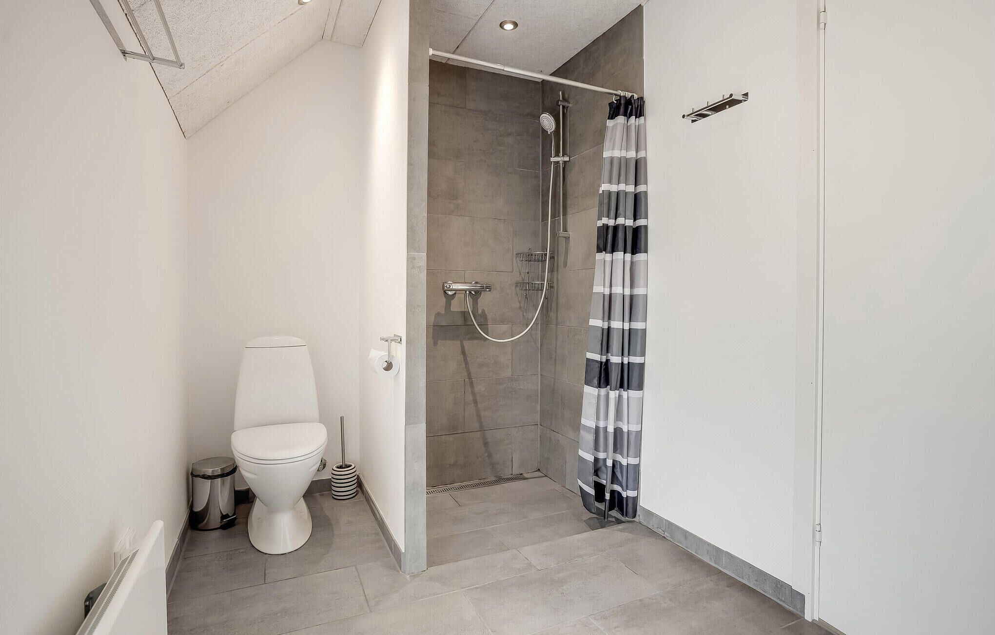 Un bagno moderno con doccia, WC e porta asciugamani.