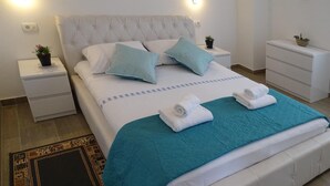 A neatly made bed with a teal bedspread, two pillows, and two rolled towels. - 2 bedroom lovely apartment in Zadar (Zadar)