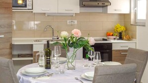 A dining area with a table set for two, a wine bottle, and a vase with flowers. - 2 bedroom lovely apartment in Zadar (Zadar)