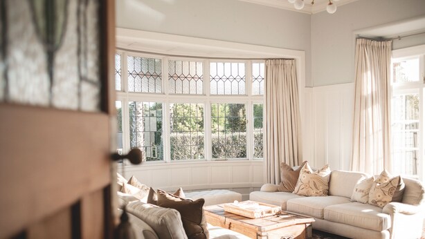 A living room with a large window, a sofa, a coffee table, and a patterned rug. - Cedar House (Gisborne)