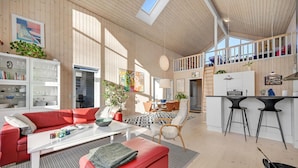 A spacious living area with a red sofa, a dining table, and a kitchen with a bar area.