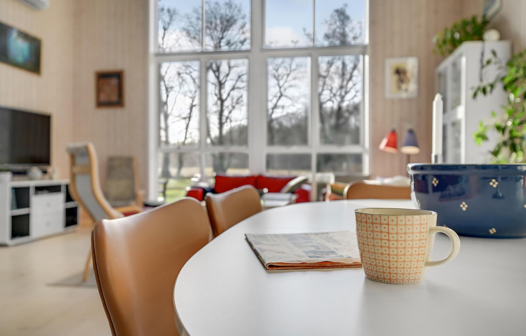 Un comedor con una mesa, sillas, un periódico y una taza.