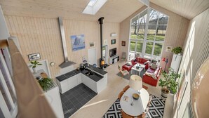 A spacious living area with a large window, a fireplace, and a kitchen with modern appliances.