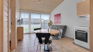 A modern kitchen with a round table, two chairs, a sofa, and a built-in oven. - Lovely home in Pandrup with kitchen (Pandrup)