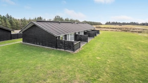 A modern building with a sloped roof, large windows, and a well-maintained lawn. - Lovely home in Pandrup with kitchen (Pandrup)