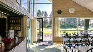 A restaurant with a bar area, outdoor seating, and a view of a golf course. - Stunning home in Pandrup with kitchen (Pandrup)