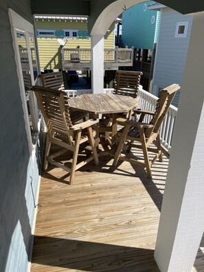Een houten terras met een tafel en stoelen, omgeven door witte leuningen.