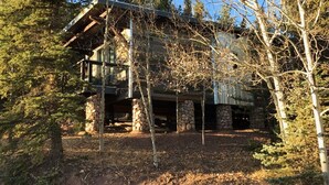 A rustic cabin with a stone foundation, wooden beams, and a metal roof.