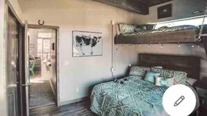A bedroom with a bunk bed, a patterned bedspread, and a framed picture on the wall.