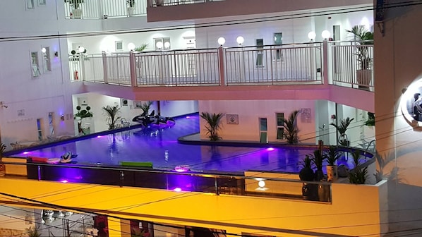 Une piscine intérieure à plusieurs niveaux, dotée d’un élément aquatique central et agrémentée de plantes décoratives tout autour.