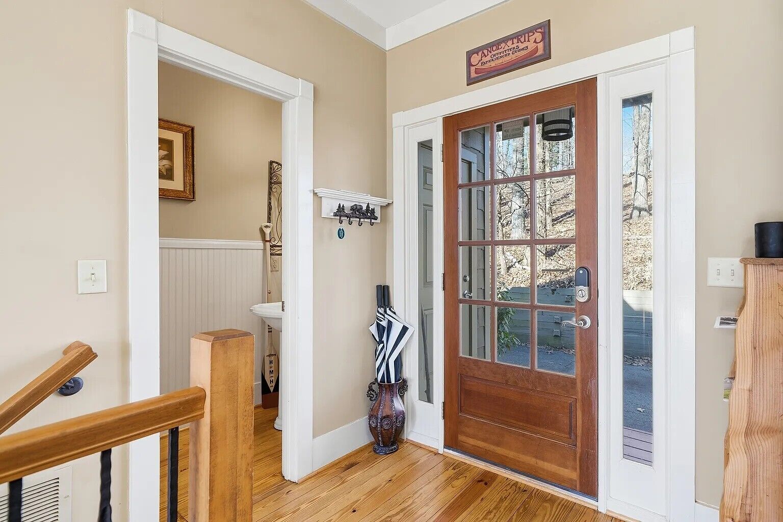 A hallway with a wooden door, a vase, and a sign above the door.
