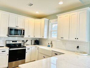 Uma cozinha moderna com armários brancos, eletrodomésticos de aço inoxidável e bancada de mármore.