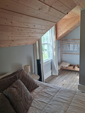 A bedroom with a bed, a bedside table, a lamp, a window, and a wooden ceiling. - Farmhouse with game room, creek and fire pit (Johnson City)