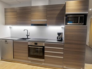 Een koelkast, een magnetron, een vaatwasser, kookgerei, borden en bestek