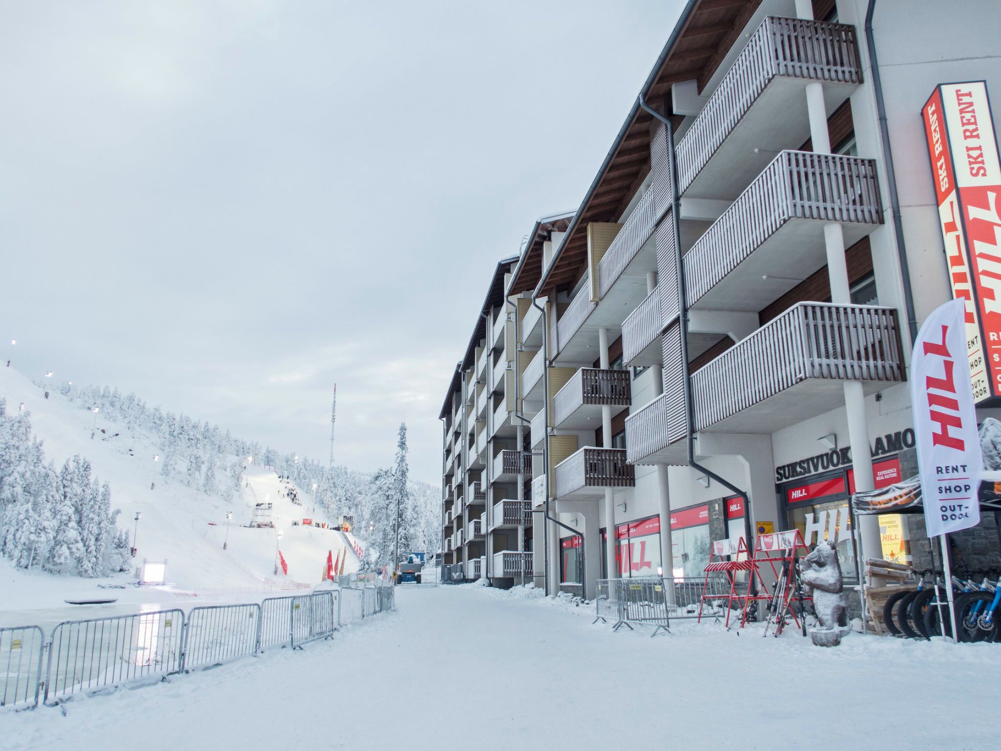 A multi-story building with balconies, a ski rental sign, and a shop named 'Hill'.