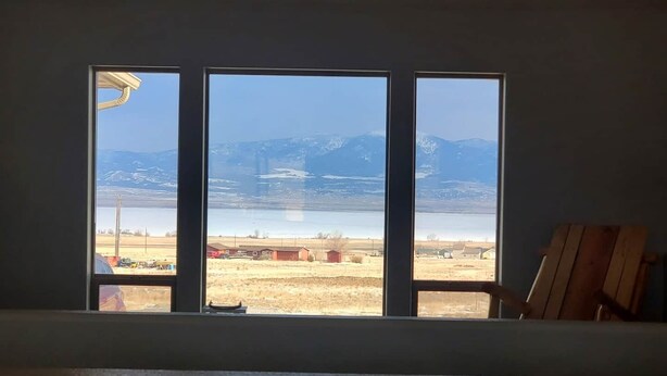 A room with a large window overlooking a rural landscape with mountains and a body of water. - Classy 3-Bedroom Fishing Cottage with amazing lake and mountain views (Townsend)