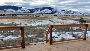 A wooden deck with a metal railing overlooking a snowy landscape with mountains in the distance. - Classy 3-Bedroom Fishing Cottage with amazing lake and mountain views (Townsend)