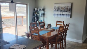 A dining area with a wooden table and chairs, a ceiling fan, and a painting on the wall. - Classy 3-Bedroom Fishing Cottage with amazing lake and mountain views (Townsend)