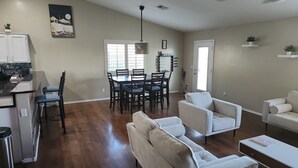 A spacious living area with a dining table, two sofas, and a kitchen area with a refrigerator and bar stools. - Desert Valley Stay - Mountain Views (Phoenix)