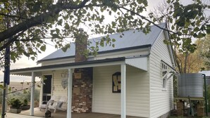 A white two-story house with a covered porch, brick chimney, and a sign reading "The Creek School House." - Two Creeks School House (Forest Reefs)