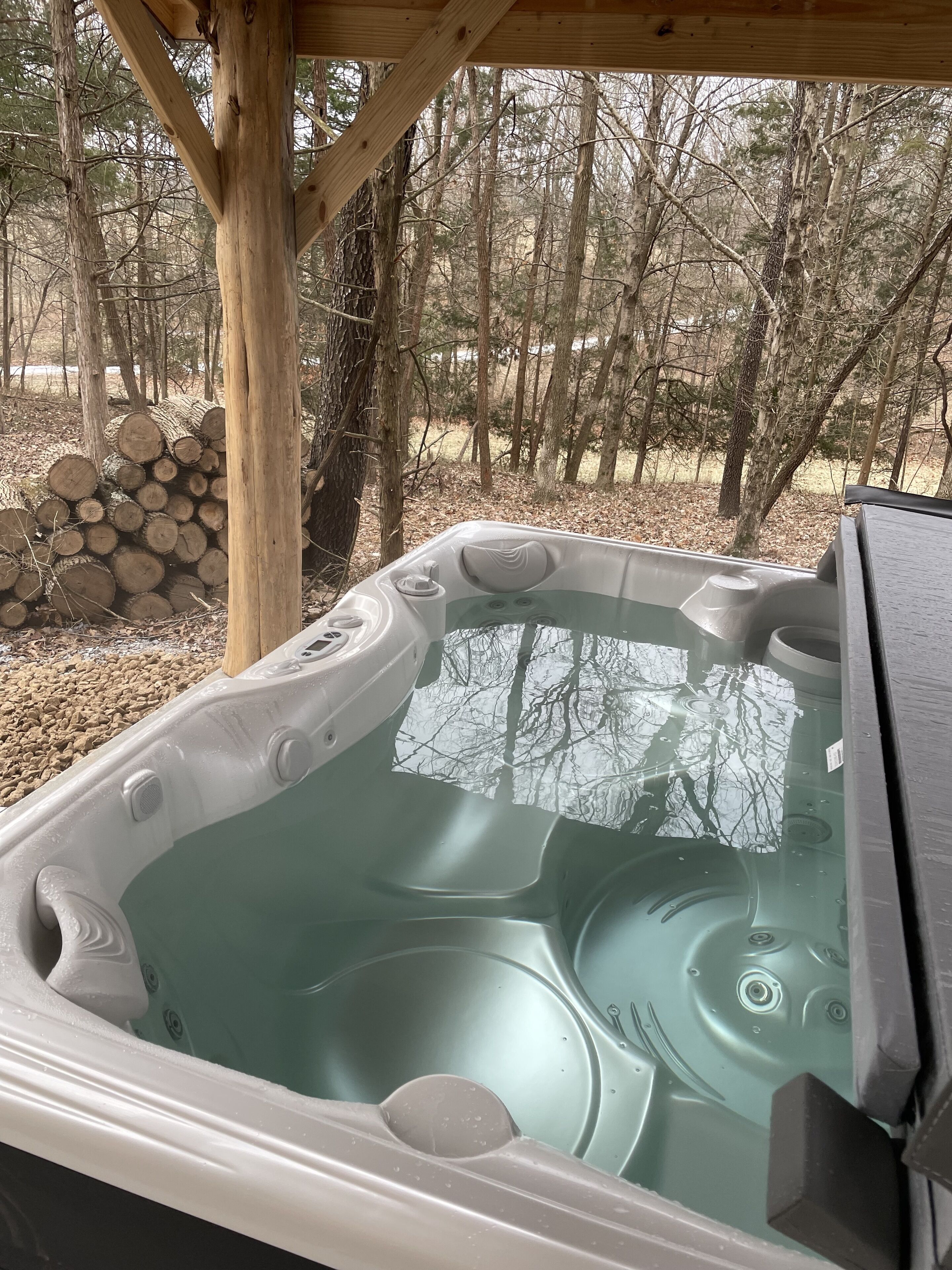 Ein Whirlpool mit einer Holterrasse und Blick auf einen Wald.