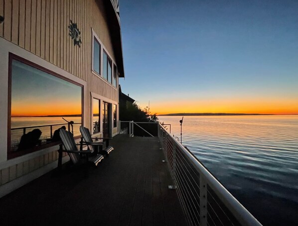 Relax on the spacious deck with a view of the water, surrounded by lounge chairs and a dining area.
