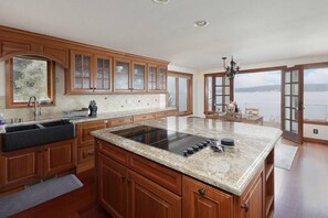 Enjoy a scenic view from the kitchen window, where a large island with a stovetop and ample counter space is complemented by cabinetry.