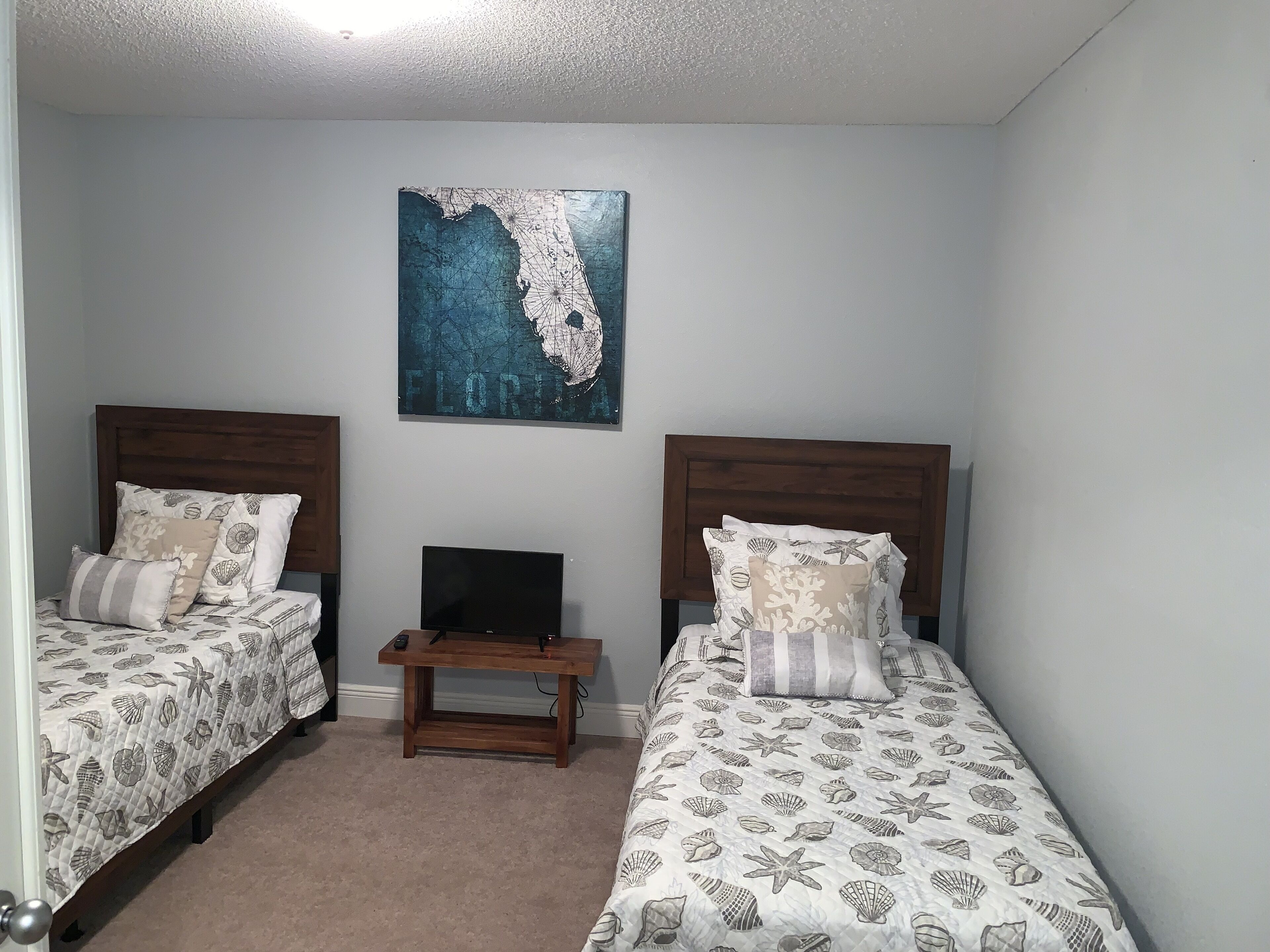 A bedroom with two beds, a small table, and a wall map.