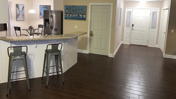 A modern kitchen with a granite countertop, stainless steel appliances, and bar stools.