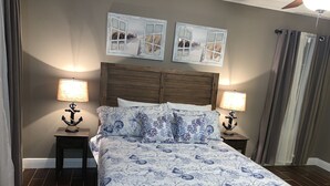 A bedroom with a bed, two nightstands, and two wall-mounted lamps.