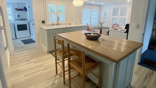 A modern kitchen with a central island, wooden chairs, and a pendant light. - Chic cottage, Vamo area, close to beaches, pet friendly, kayaks, large backyard  (Sarasota)