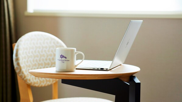 A laptop on a small wooden table with a white mug beside it. - Hotel Monte Hermana Tokyo (Tokyo)