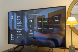 A hotel room with a flat-screen TV displaying a streaming service interface.