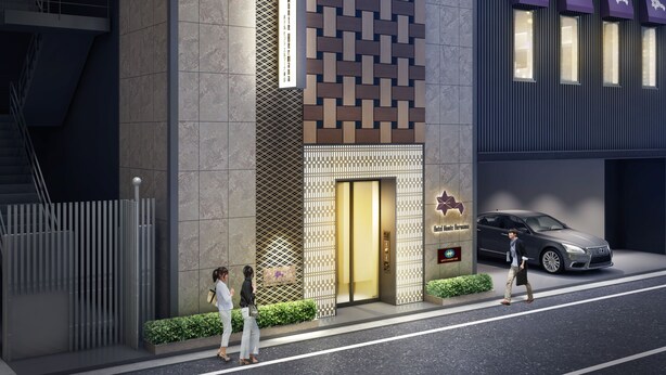En moderne hotelindgang med en mønstret facade, en synlig elevator og en parkeret bil.