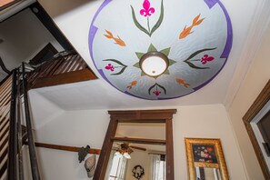 Eine Decke mit floralem Dekor, eine Holztreppe und ein gerahmtes Bild an der Wand.