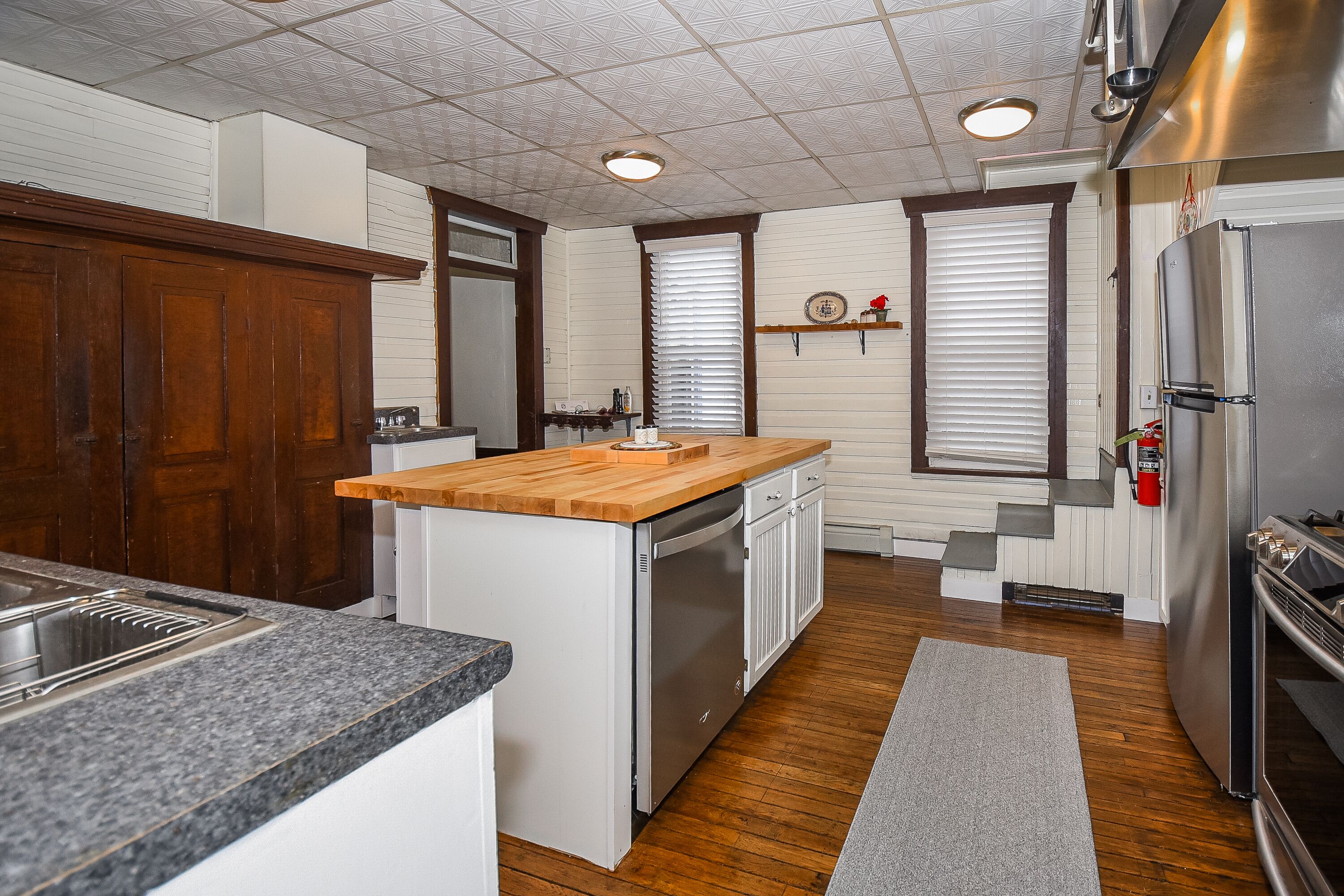 A kitchen with a granite countertop, white cabinets, a stainless steel refrigerator, and a wooden island.