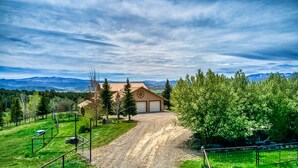 Une maison à deux étages avec un garage, entourée d’une propriété clôturée et dotée d’une allée gravillonnée.