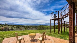 Une terrasse avec une table et des chaises, un escalier et une vue sur les montagnes.
