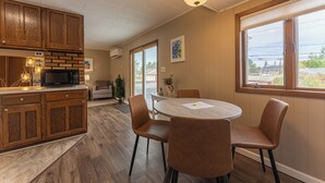 A kitchen with wooden cabinets, a microwave, and a dining area with a round table and chairs. - Vacation UniquEly home in town, with patio (Ely)