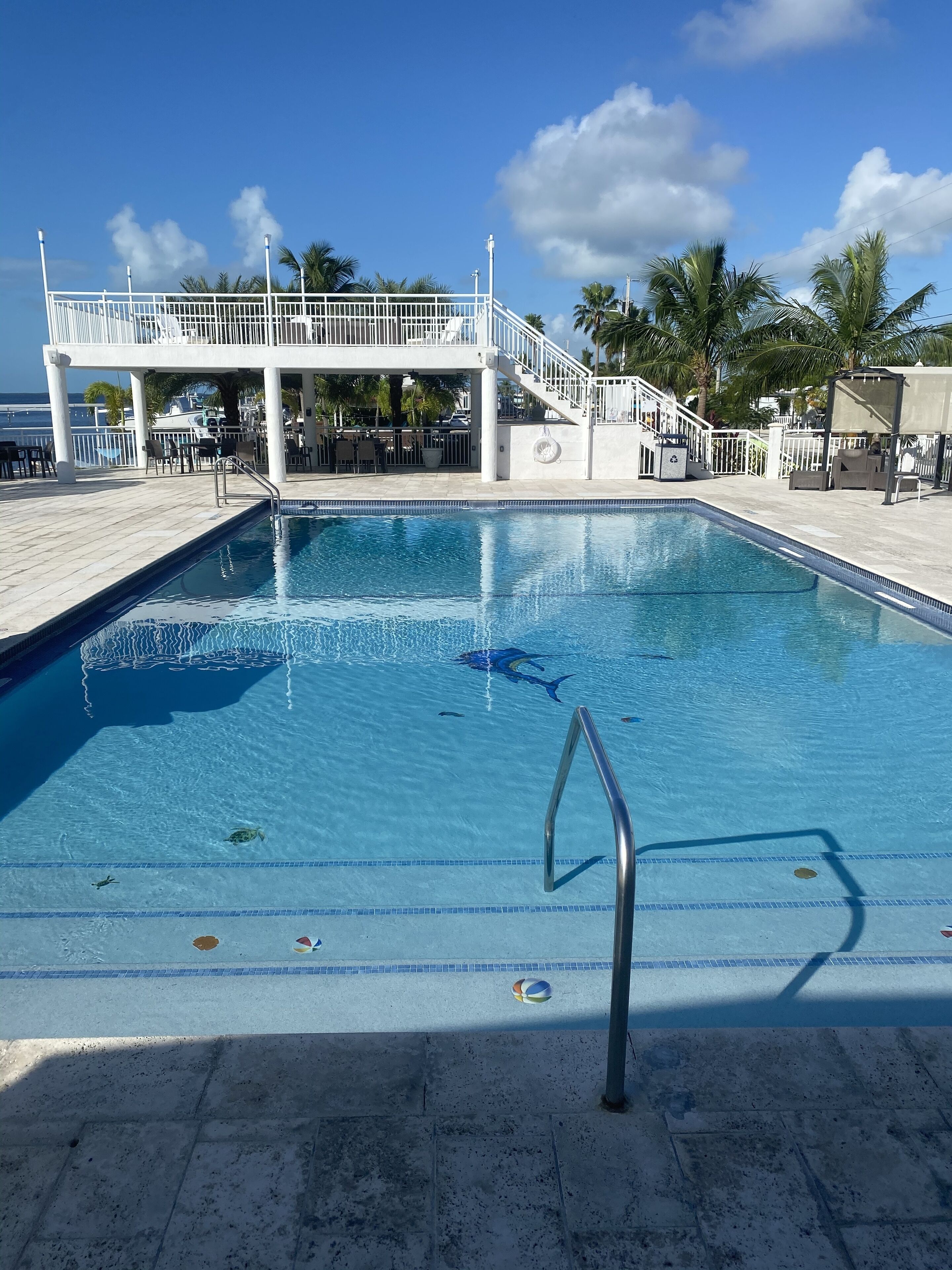 A swimming pool with a lifeguard stand, lounge chairs, and a covered seating area.