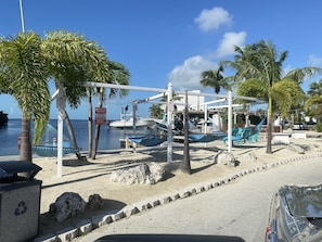 A beachside area with a hammock, lounge chairs, and a boat dock.