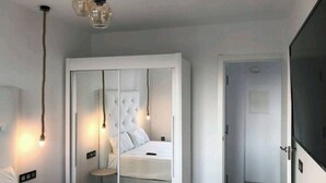 A modern bedroom with a bed, a mirror, and a wardrobe.