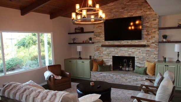 A living room with a fireplace, green cabinets, a television, and a large window. - Relaxing Mountain View Retreat with Pool & Spa! (Bonita)
